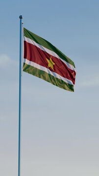 Suriname, Paramaribo: Cinematic Vertical Waving National Flag Against Blue Sky