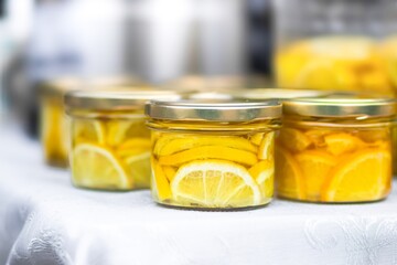 Jars filled with vibrant yellow lemon slices are neatly arranged on a white tablecloth, showcasing homemade preserves and the essence of fresh citrus flavors