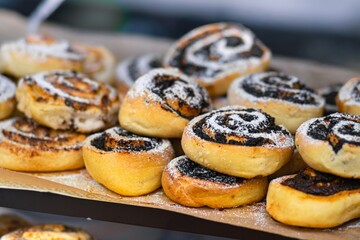 Freshly baked cinnamon rolls with swirls of chocolate and dusted with powdered sugar on a display tray, showcasing delicious pastry treats for dessert lovers