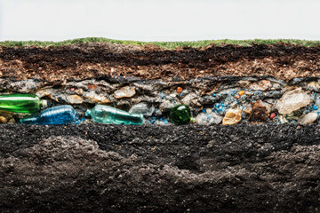 Obraz premium Cross-sectional view of soil layers revealing embedded discarded glass bottles illustrating environmental pollution and the impact of waste in underground ecosystems