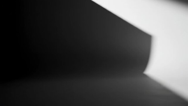 Cinematic slow movement of a large, angular shadow sweeping across a perfectly clean, pristine white studio wall creating a minimalist void quiet, white, empty