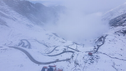 Aerial photography of a winding road in the mountains with serpentines and curves. Photography of transfagarasan road in Sibiu county, Romania. Photo was shot from a drone at a higher altitude.
