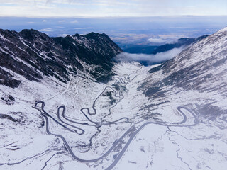 Aerial photography of a winding road in the mountains with serpentines and curves. Photography of transfagarasan road in Sibiu county, Romania. Photo was shot from a drone at a higher altitude.