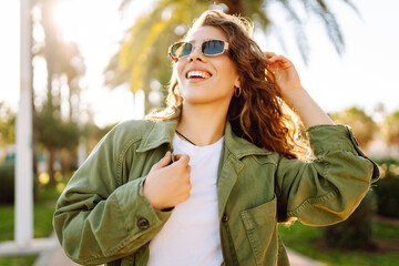 A cheerful woman is enjoying herself in a sunny park. A backpacker wearing sunglasses enjoys a walk...
