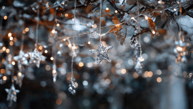 A sparkling silver star ornament hangs from a branch, surrounded by a dreamy bokeh of warm golden fairy lights and cool festive decorations. - Powered by Adobe