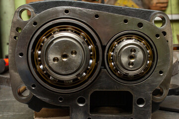 Disassembled industrial compressor or pump housing, revealing two large, precision ball bearings...
