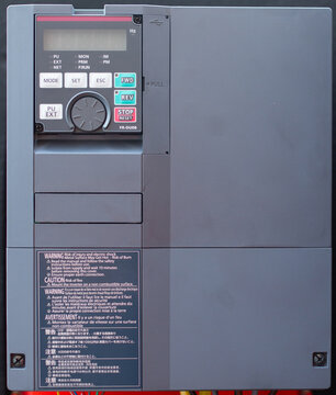 Variable Frequency Drive (VFD) or power inverter control unit with a keypad, display, and multilingual warning labels for electrical engineering and industrial automation