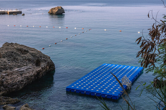 A pier made of plastic pontoons for outdoor recreation. Plastic pontoons for piers and piers. Modular plastic pontoon on the shore of the Mediterranean Sea. A pier for swimming.
