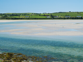 Beautiful view of a wide river near green hills on the horizon under white clouds.