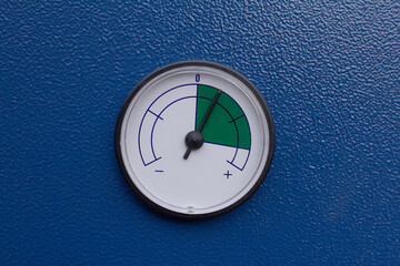 Circular pressure or filter indicator gauge on a bright blue industrial machine panel, displaying a reading in the optimal green sector for operational status monitoring and maintenance