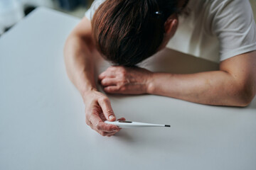 体温計を持って倒れるシニア女性