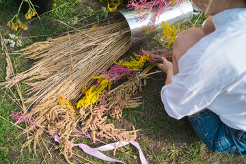 Woman making traditional flower crown with wild flowers for midsummer celebration or bridal party