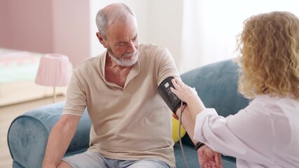 Medical professional performing blood pressure measurement for senior patient during home health consultation, focusing on cardiovascular wellness and geriatric care monitoring