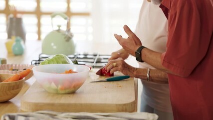 Elderly couple preparing a healthy meal, chopping vegetables on a wooden cutting board in their kitchen