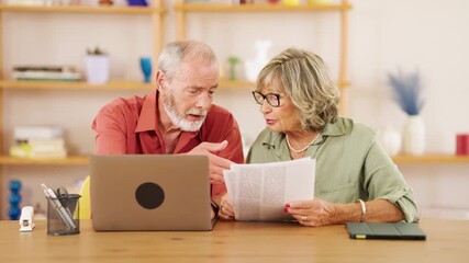 Elderly couple reviewing paperwork and using laptop, discussing and collaborating on financial matters or online tasks - Powered by Adobe