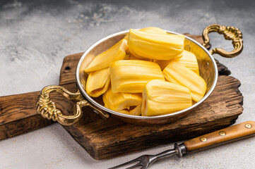 Sweet, golden jackfruit pods (bulbs) in a traditional metal bowl with a fork. Exotic tropical snack or dessert with copy space © Mironov