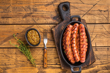 Juicy, smoky fried sausages on a wooden board with herbs and fork. High-quality image for...