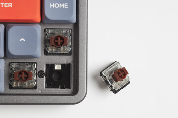Top-down view of mechanical keyboard with brown switch removed, showing switch socket and detailed switch mechanism
