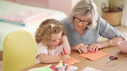 Grandmother enjoying creative time with her curly-haired granddaughter. Affectionate family members drawing and making greeting cards at home - Powered by Adobe
