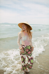 A girl smiles in a national Chinese hat on the beach