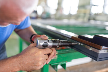 A worker in an aluminum and PVC factory works on profiles.