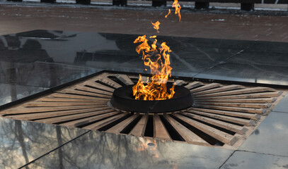 A symbolic memorial eternal flame burning in a circular structure with reflective surface