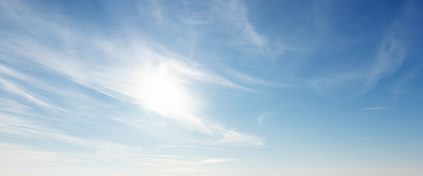 Sun is shining in wide blue sky with white cirrus clouds, natural panoramic background