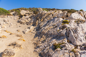 Vast blue sky over rugged rocky cliffs and sandy dunes along a coastal landscape
