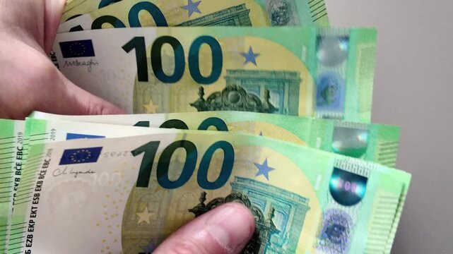 Close-up of a man's hands counting a stack of one hundred euro banknotes