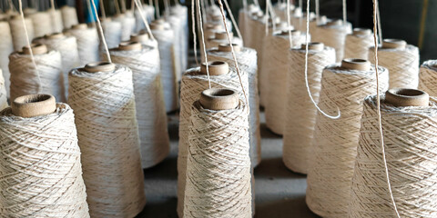 Naturl colored yarn spools in fabric production in textile factories.