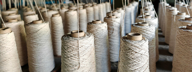 Naturl colored yarn spools in fabric production in textile factories.