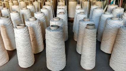 Naturl colored yarn spools in fabric production in textile factories.
