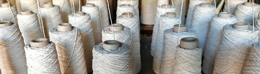 Naturl colored yarn spools in fabric production in textile factories.