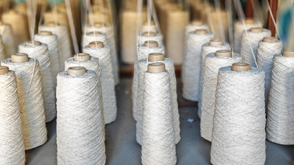 Naturl colored yarn spools in fabric production in textile factories.