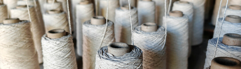 Naturl colored yarn spools in fabric production in textile factories.