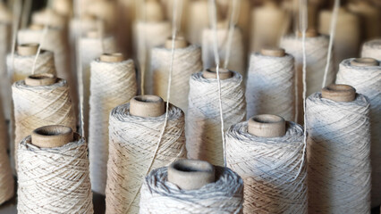 Naturl colored yarn spools in fabric production in textile factories.