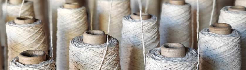 Naturl colored yarn spools in fabric production in textile factories.