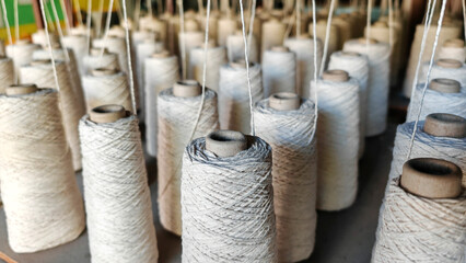 Naturl colored yarn spools in fabric production in textile factories.