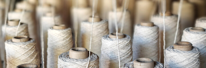 Naturl colored yarn spools in fabric production in textile factories.