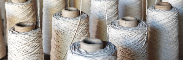 Naturl colored yarn spools in fabric production in textile factories.