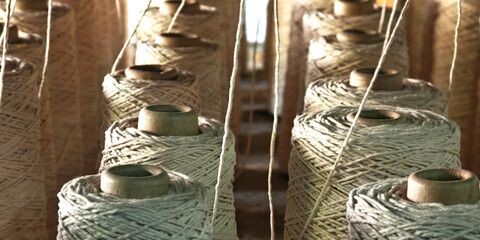 Naturl colored yarn spools in fabric production in textile factories.