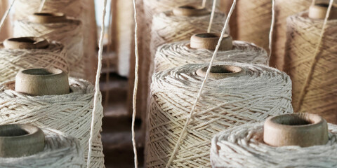 Naturl colored yarn spools in fabric production in textile factories.