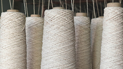 Naturl colored yarn spools in fabric production in textile factories.