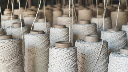 Naturl colored yarn spools in fabric production in textile factories.