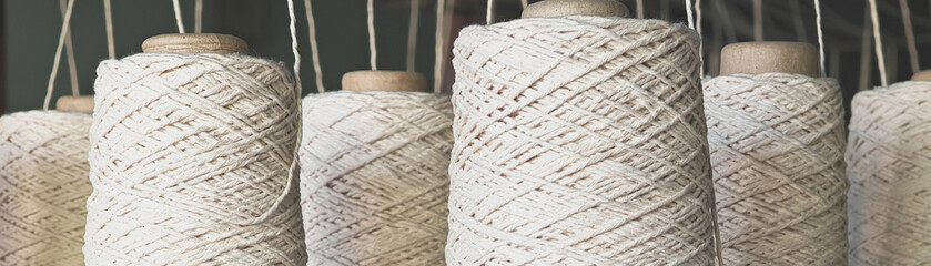 Naturl colored yarn spools in fabric production in textile factories.