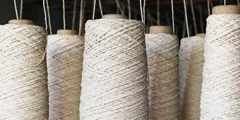 Naturl colored yarn spools in fabric production in textile factories.