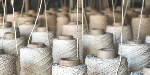 Naturl colored yarn spools in fabric production in textile factories.