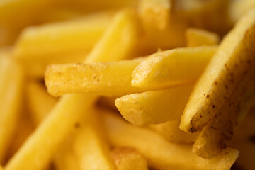 A delicious pile of golden french fries. Macro photography captures the crispy texture, creating an appetizing food background for fast food or menu concepts.