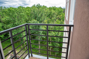 Obraz premium Modern balcony with metal railing overlooking green forest.