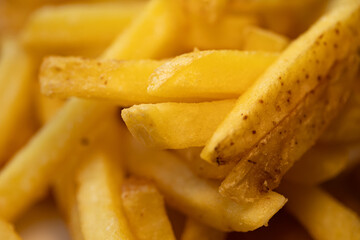 A delicious pile of golden french fries. Macro photography captures the crispy texture, creating an appetizing food background for fast food or menu concepts.